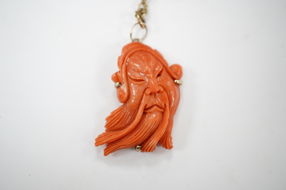 A single strand coral bead necklace, with a coral pendant carved as the face of a gentleman, overall 48cm. Condition - fair